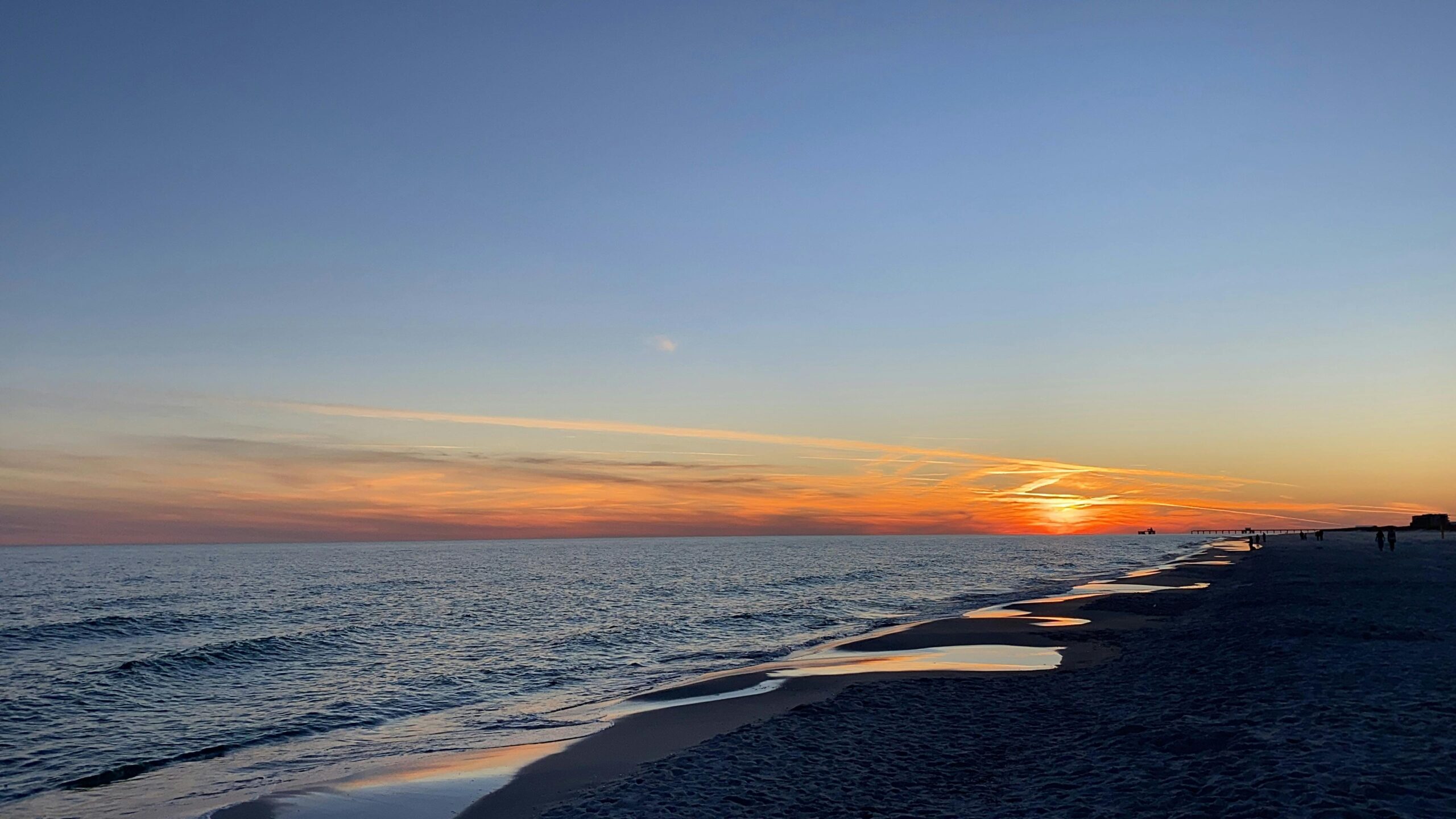 Breathtaking sunset view over the Gulf Shores beach with gentle waves and colorful sky.