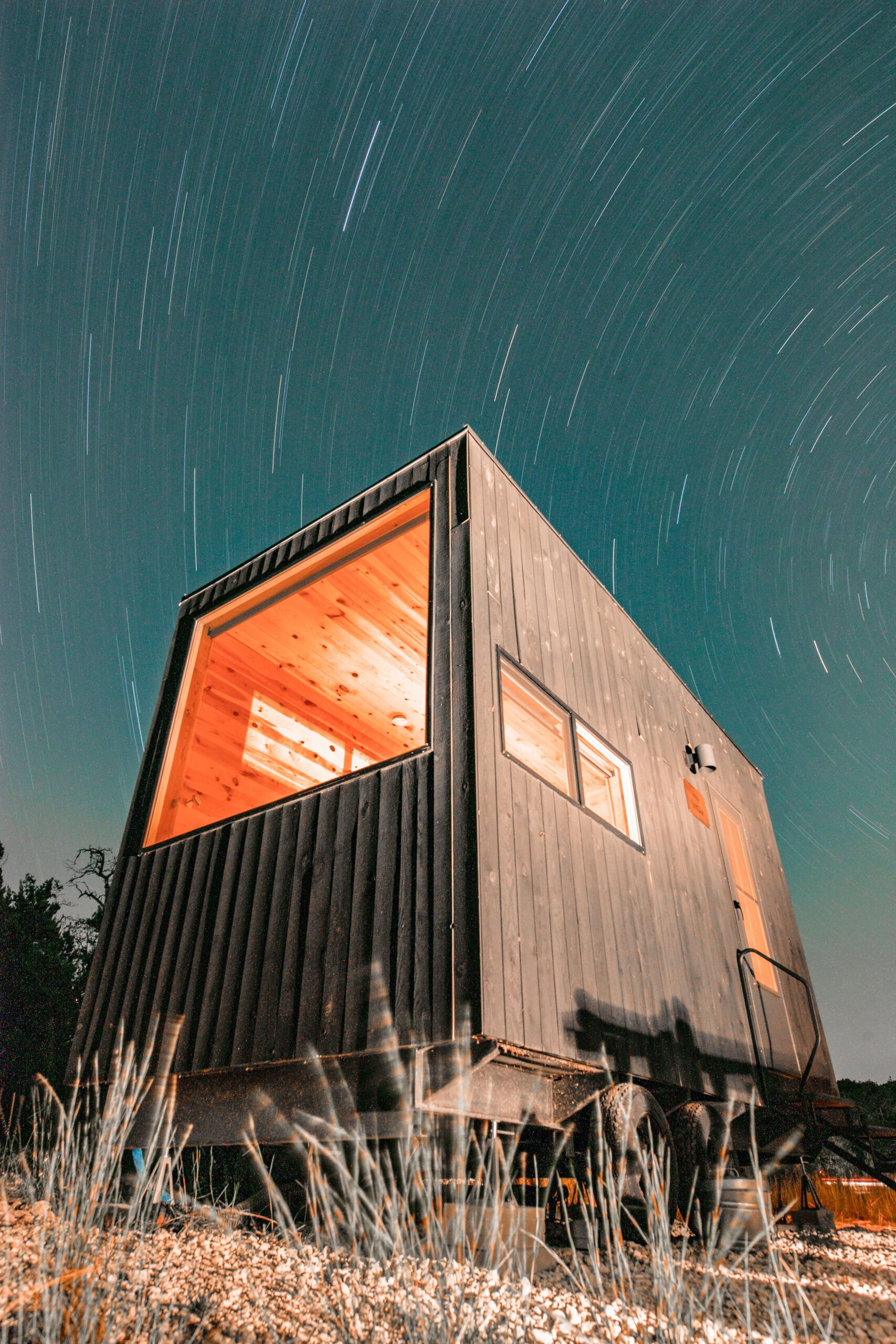 Night view of a modern tiny house illuminated under a starry sky in Wimberley, Texas.